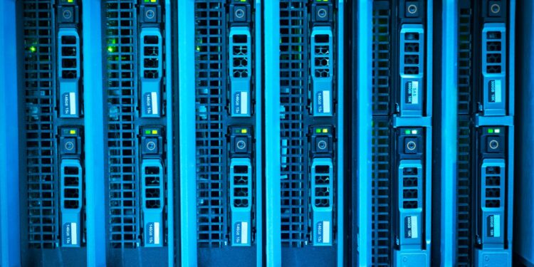 Responsável de TI conferindo o painel de rotina de backup enquanto a equipe da empresa segue operando ao fundo